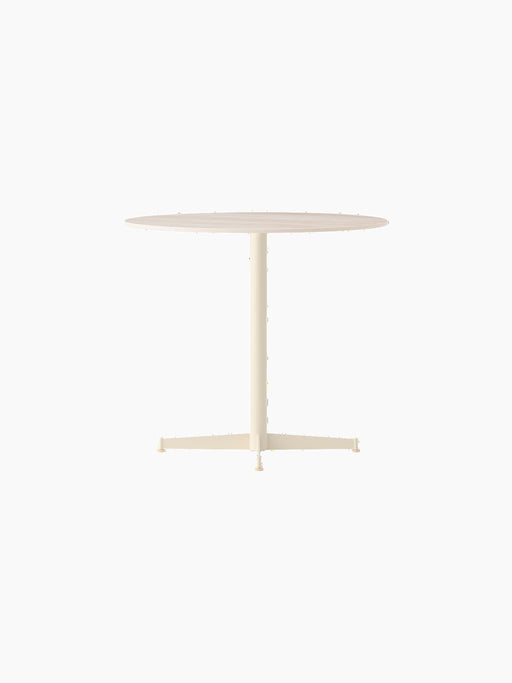 Angle view of the Nook Dining Table, featuring a round Estremoz Marble top and an ivory powder-coated steel four-star base.