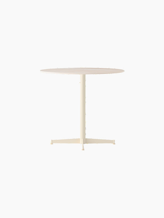 Angle view of the Nook Dining Table, featuring a round Estremoz Marble top and an ivory powder-coated steel four-star base.