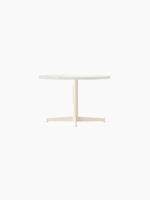 Angled view of the Nook Lounge Table featuring a round, light-coloured tabletop and an ivory four-star pedestal base.