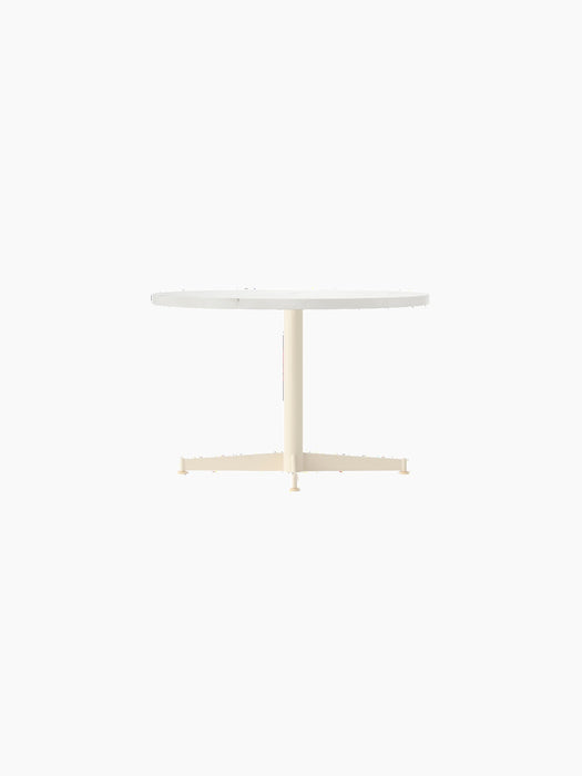 Angled view of the Nook Lounge Table featuring a round, light-coloured tabletop and an ivory four-star pedestal base.