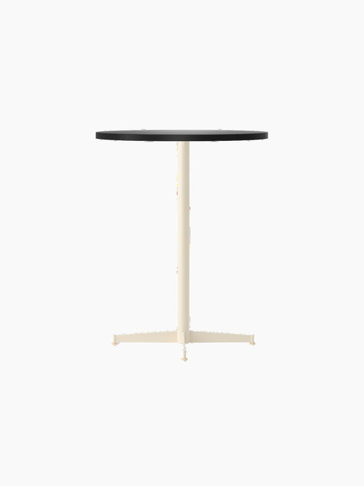An angle view of the Nook Counter Table, featuring a round, charcoal linoleum tabletop and a slender, ivory-coloured base.