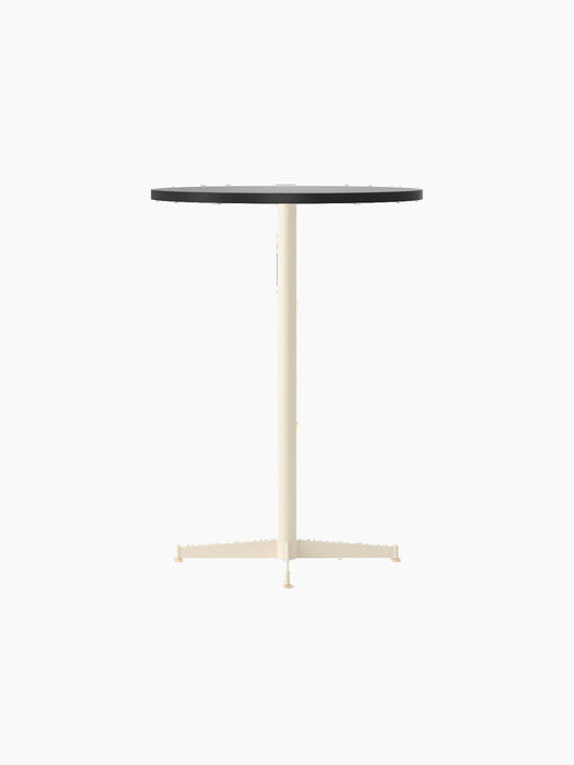 The Nook Bar Table seen from an angle, showing its dark circular tabletop and slender ivory-coloured pedestal base.