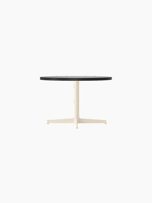 Side view of the Nook Lounge Table with a round, charcoal linoleum top and an ivory-coloured, four-star metal base.