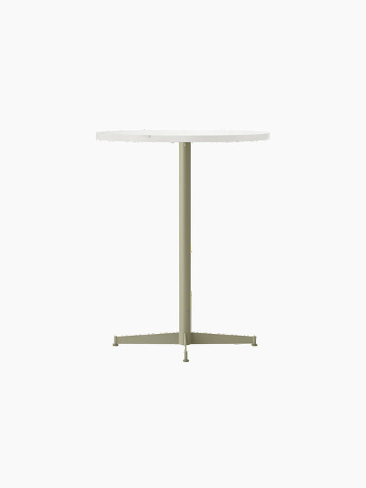 Angled shot of the Nook Counter Table. It has a round, light stone top and a slender olive base with a four-pronged foot.