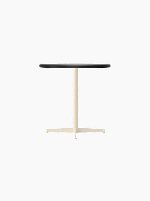 A Nook Dining Table shown from the side, with a round black tabletop and a slim, ivory-coloured, four-star pedestal base.