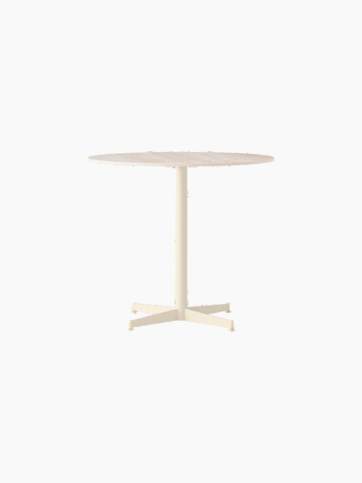 Front view of the Nook Dining Table with a round, light stone tabletop, a slim ivory central stem and four-star base.
