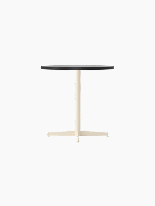 Angle view of the Nook Dining Table with a charcoal linoleum top and an ivory powder-coated steel four-star pedestal base.