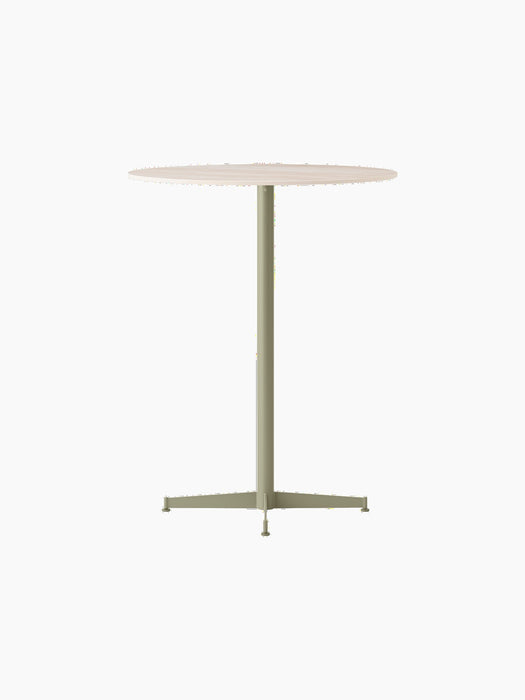 The Nook Bar Table shown at an angle, featuring a round, light-coloured tabletop and a tall pedestal base in an olive finish.