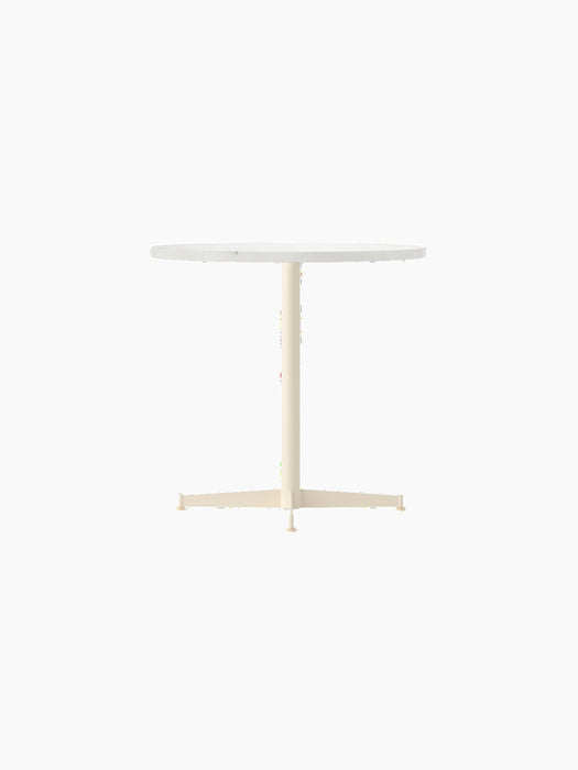 Angled view of the Nook Dining Table, featuring a round white top and a slender, ivory-coloured pedestal base with four feet.