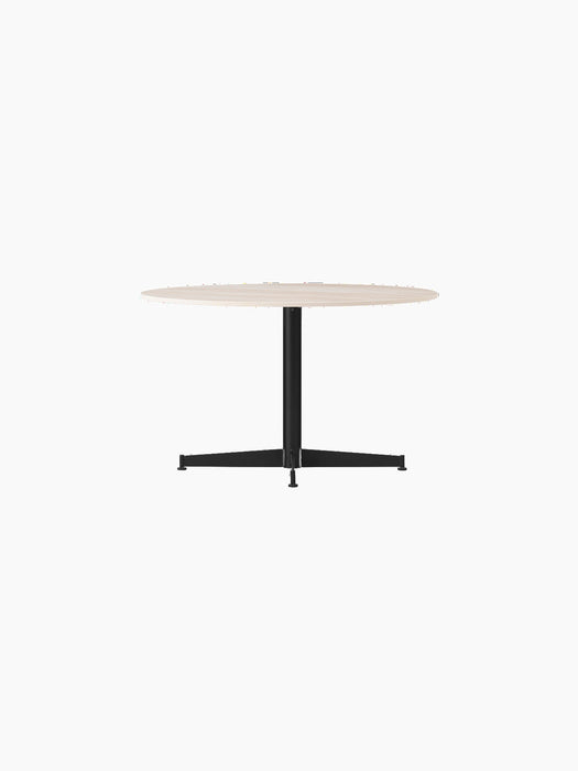 The Nook Lounge Table, shown at an angle, with a round, light-coloured stone top and a black four-star metal base.