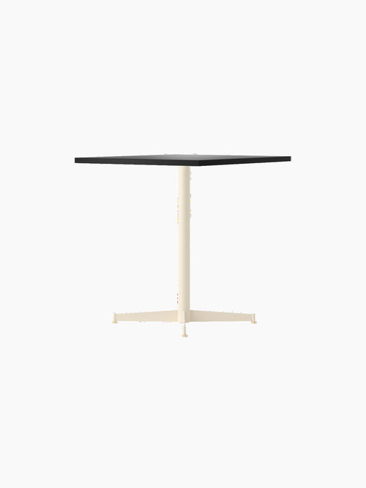 The Nook Dining Table shown with a dark rectangular top and a slim, ivory-coloured, four-star pedestal base.
