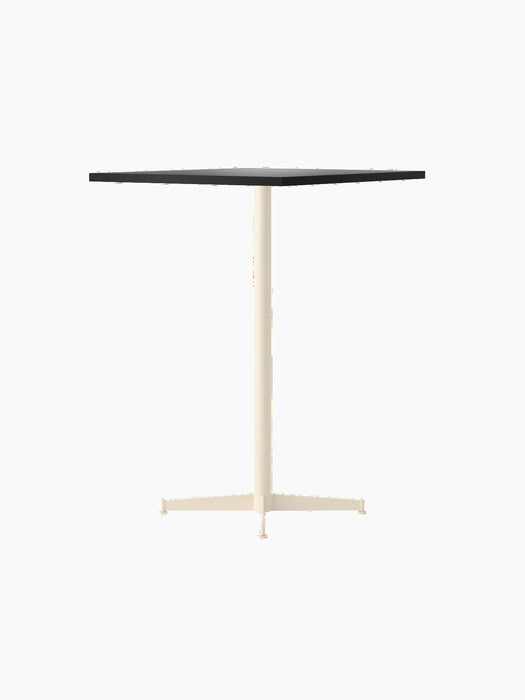 The Nook Bar Table, angled to show its rectangular charcoal linoleum top and slender, four-pronged ivory steel base.