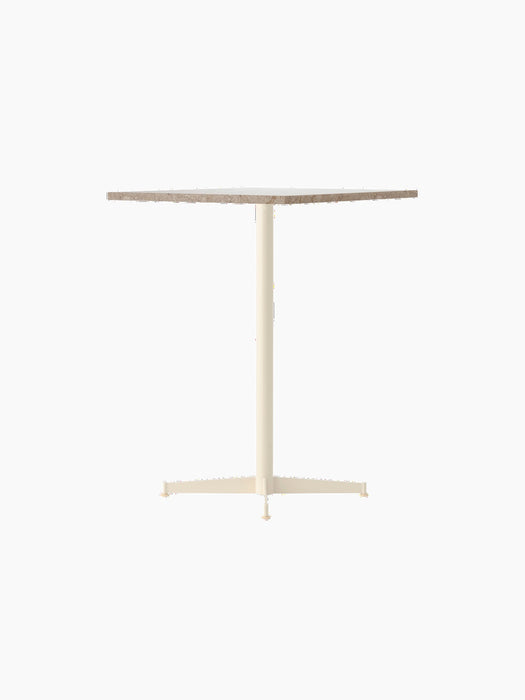 An angle view of the Nook Counter Table, featuring a textured Kunis Breccia stone top and a slender ivory pedestal base.