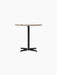 Front view of the Nook Dining Table with a round Kunis Breccia stone top and a black powder-coated steel four-star base.