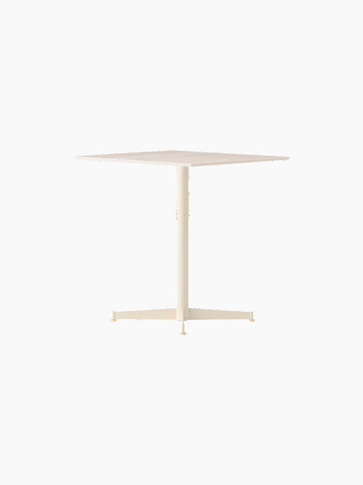 Angle view of the ivory Nook Dining Table, which has a square top, a single central stem, and a slim, four-star base.