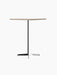 An angle view of the Nook Bar Table, featuring a round, textured stone top and a slender black steel pedestal base.