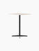 Angled view of the Nook Counter Table with a square, light-coloured top and a black powder-coated steel pedestal base.
