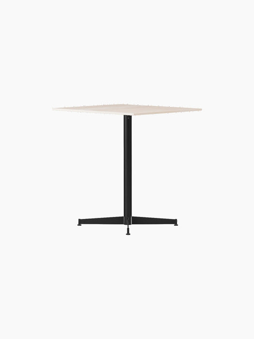 Angled view of the Nook Dining Table with a square, light-coloured top and black powder-coated steel four-star base.