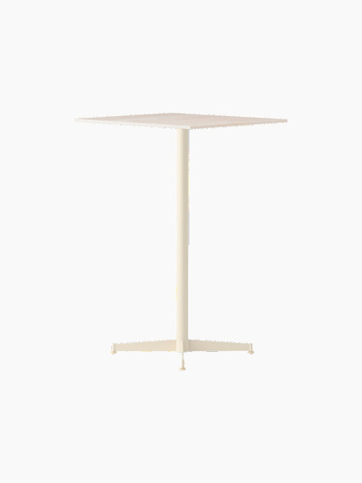 The Nook Bar Table, shown at an angle, features an ivory finish, a square top, and a central column on a four-legged base.