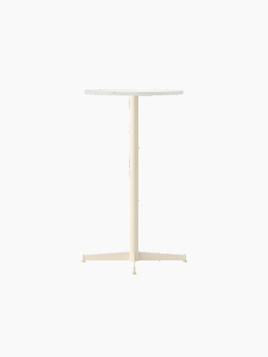 An angled view of the Nook Bar Table, featuring a round Estremoz marble top and a slim ivory-coloured steel base.