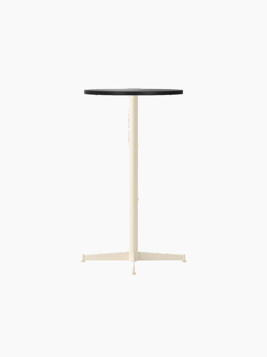 The Nook Bar Table with a round charcoal linoleum tabletop and a tall, ivory powder-coated steel base with four feet.