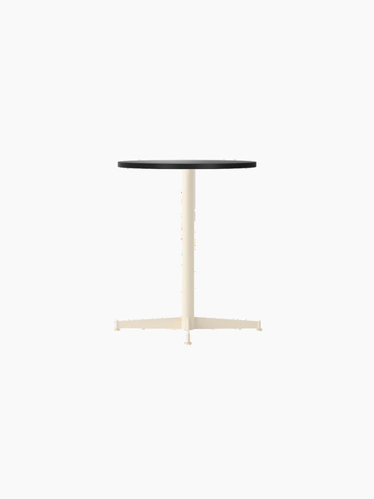 Angle view of the Nook Dining Table with a round charcoal linoleum top and a slim, ivory powder-coated steel four-star base.