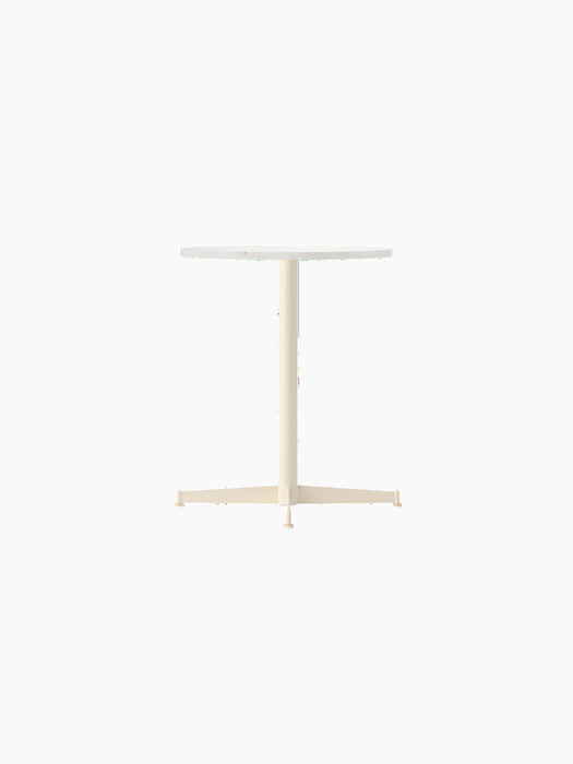 An angled view of the Nook Dining Table with a round Estremoz marble top and an ivory powder-coated steel four-star base.