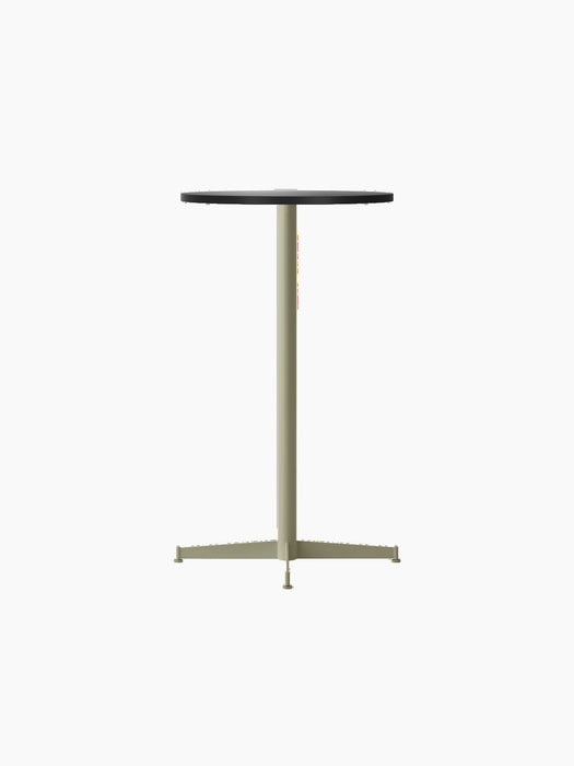The Nook Bar Table, shown at an angle, with a round charcoal linoleum tabletop and a slim olive green steel base.