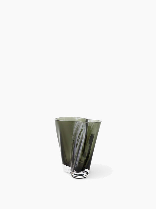An angled view of the Aer Vase 19, a sculptural vase in smoky green glass with a twisted, undulating shape and a clear base.