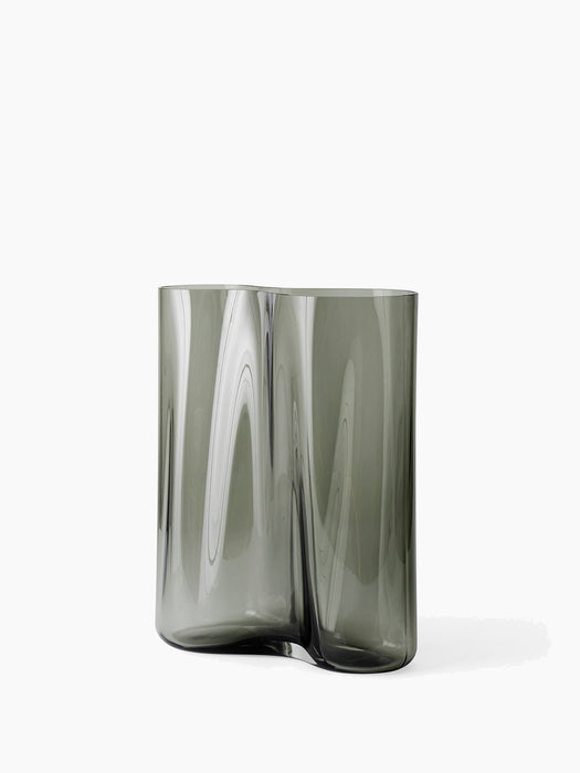 A small Aer Vase made from smoky grey rippled glass, creating an undulating silhouette, pictured against a white background.