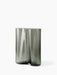 A small Aer Vase made from smoky grey rippled glass, creating an undulating silhouette, pictured against a white background.