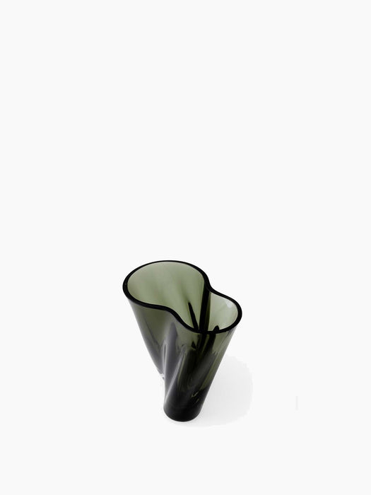 High-angle view of Aer Vase 19, a sculptural vase in dark, smoky green glass with an undulating rim, on a white background.