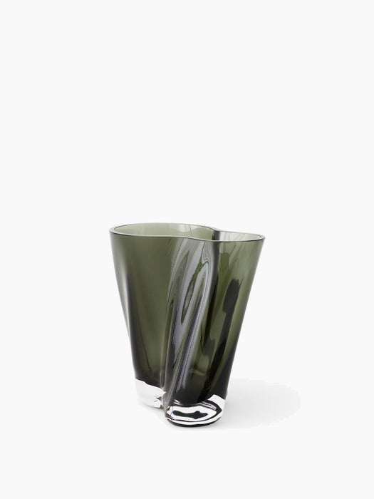 An angled view of the Aer Vase, a twisted, sculptural glass vase in a dark, smoky green hue with a thick, clear base.