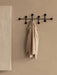 The black Afteroom Coat Hanger Large mounted on a beige wall, with a beige linen shirt hanging from one of the central hooks.
