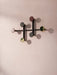 A minimalist black metal Afteroom Coat Hanger with round hooks in multiple colors, fixed to a pale pink, textured wall.