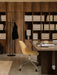 An office with an Androgyne Table, a yellow Harbour Chair, Afteroom Coat Stand, and Nonna Lamp against dark wood shelving.