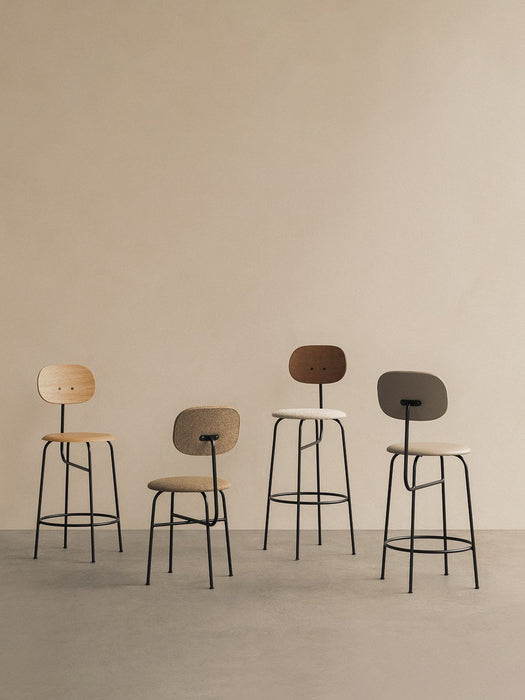 A studio shot of four Afteroom Counter Chair Plus variations, with different heights, wood finishes, and upholstery.