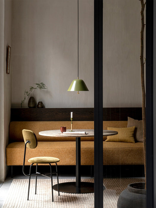 An Afteroom Dining Chair Plus in mustard yellow stands by a round table and matching upholstered bench in a cosy dining nook.