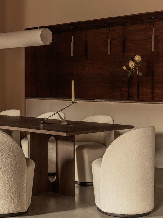 The dark wood Androgyne Dining Table with Tearoom Chairs and an Interconnect Candle Holder, lit by a Hashira Pendant.
