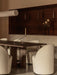 The dark wood Androgyne Dining Table with Tearoom Chairs and an Interconnect Candle Holder, lit by a Hashira Pendant.