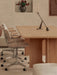 A light oak Androgyne Dining Table is shown from the side with two upholstered office chairs and a minimalist candlestick.