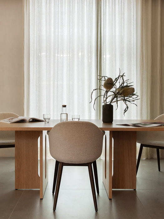 A dining room setting with the Androgyne Dining Table, Harbour Dining Chairs, and a Cyclades Vase with dried flowers on top.