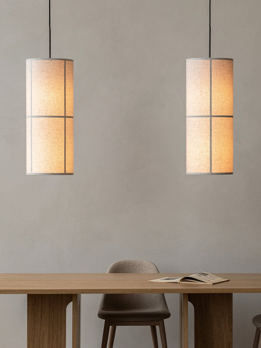 A minimalist dining room with two lit Hashira Pendant Lamps above a wooden Androgyne Rectangular Table and Harbour Chair.
