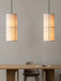 A minimalist dining room with two lit Hashira Pendant Lamps above a wooden Androgyne Rectangular Table and Harbour Chair.