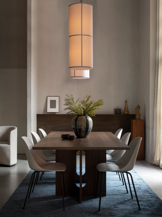 The Androgyne Dining Table and Harbour Side chairs on a Houkime Rug, illuminated by a Hashira pendant light in a dining room.
