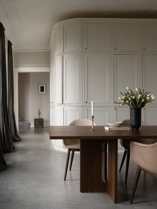 The dark oak Androgyne Dining Table with Harbour Chairs, a Duca Candle Holder, and a Cyclades vase in an elegant room.
