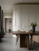 The dark oak Androgyne Dining Table with Harbour Chairs, a Duca Candle Holder, and a Cyclades vase in an elegant room.