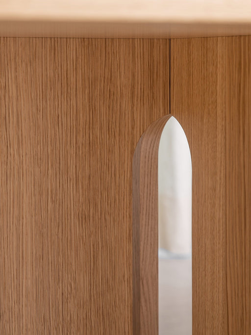 Detailed close-up of the Androgyne Dining Table base, showcasing the rich texture of natural oak and its arched cutout.