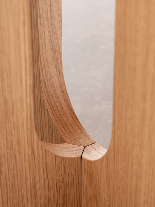 A close-up detail of the Androgyne Dining Table's sculptural base, showing the fine joinery and natural oak wood grain.
