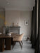 A dark Androgyne Dining Table and beige Harbour Dining Chairs in a room with a fireplace, Aer Vase and white Ribbon Basket.